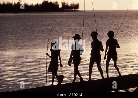 Silhouette di bambini la pesca al tramonto in Mauritius Foto Stock