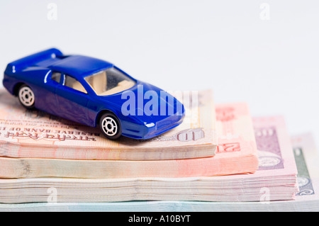 Close-up di un giocattolo auto su una pila di banconote indiano di diverse confessioni Foto Stock