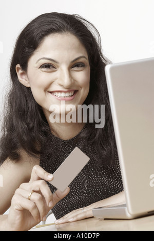 Ritratto di una giovane donna seduta davanti a un computer portatile e titolari di una carta di credito Foto Stock