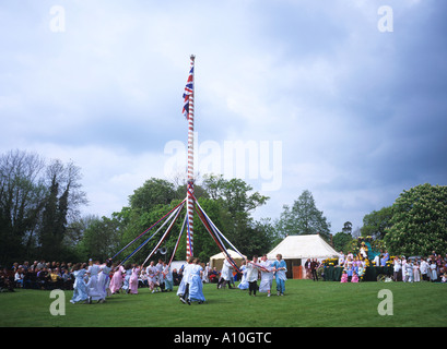 I bambini del villaggio che danzano intorno il Maypole al verde Ickwell guardato dal maggio Regina sulla sua piattaforma Bedfordshire Foto Stock