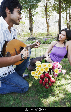 Giovane uomo suonare il mandolino con una giovane donna che guarda a lui Foto Stock