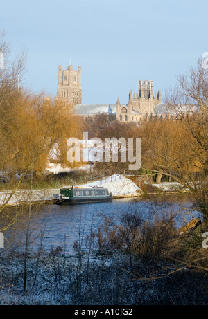 Cattedrale di Ely nella neve durante la stagione invernale con il fiume Cam e una stretta barca in primo piano Foto Stock