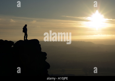 Persona guardando il tramonto da una rupe nel Parco Nazionale di Peak District Derbyshire Foto Stock