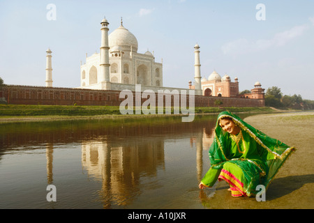 Giovane donna accovacciata sul greto del fiume, Taj Mahal, Agra, Uttar Pradesh, India Foto Stock