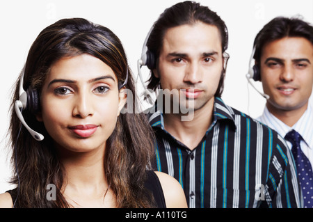 Ritratto di una giovane donna e due giovani uomini che indossano le cuffie in una riga Foto Stock