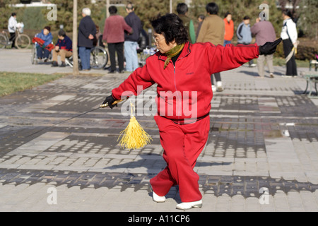 Senior Citizen balzi in avanti con la sua spada in un parco lungo Yinshui Qu, Hucheng fiume (il fossato della città), Pechino, Cina Foto Stock