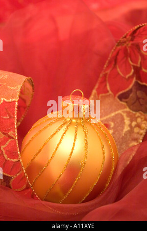 Golden ornamento di Natale con contro un setoso sfondo rosso. Foto Stock