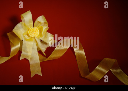 Golden bow e nastro contro uno sfondo rosso Foto Stock