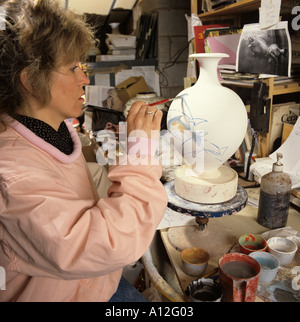 Una giovane donna lavora con molto pennello fine lavori su un vasi di ceramica in un laboratorio vicino a Stroud in Gloucestershire Foto Stock