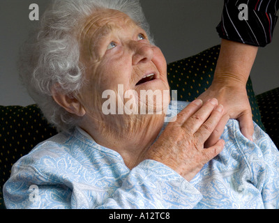 Assistenza agli anziani caregiver COMFORT mano felice sorridente senior età anziana signora guarda e tocca la mano confortante del caregiver Foto Stock