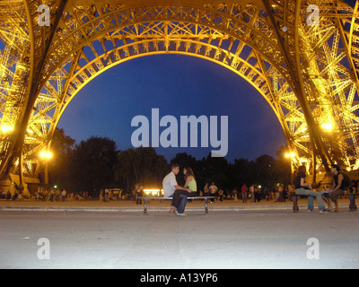Coppia romantica seduto vicino insieme sotto la Torre Eiffel al tramonto Foto Stock