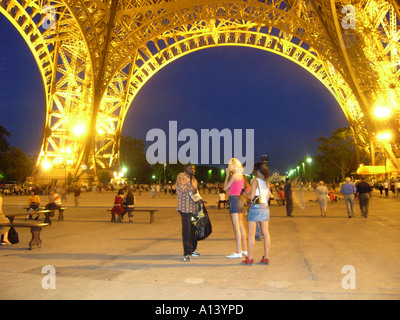 Due turisti femmina e il venditore ambulante sotto la Torre Eiffel al tramonto Foto Stock