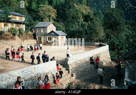 Fine del giorno di scuola in montagna himalayana. Lasciare i bambini al parco giochi sotto lo sguardo attento del loro maestro Foto Stock