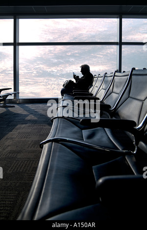 Business man in aeroporto in attesa di un telefono per la messaggistica di testo alla fine di un lungo viaggio , Filadelfia Pennsylvania USA Foto Stock