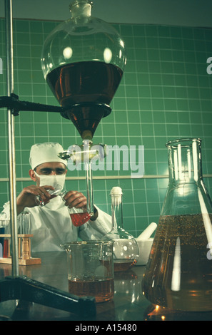 Uno scienziato che indossa un cappello protettivo e la maschera di impasti fluidi in un esperimento di laboratorio Foto Stock