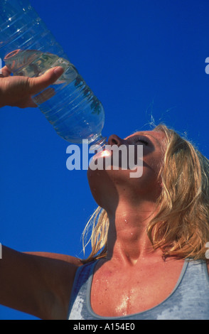 Una donna assume una bevanda a partire da una bottiglia di acqua dopo il lavoro Foto Stock