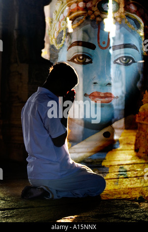 Giovani indiani uomo prega nel tempio Lepakshi con Krishna immagine composita. Andhra Pradesh, India Foto Stock