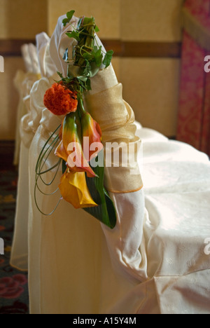 Chiudere verticale di arancio brillante calla lily flower pone la decorazione della schienali di poltrone a un matrimonio Foto Stock