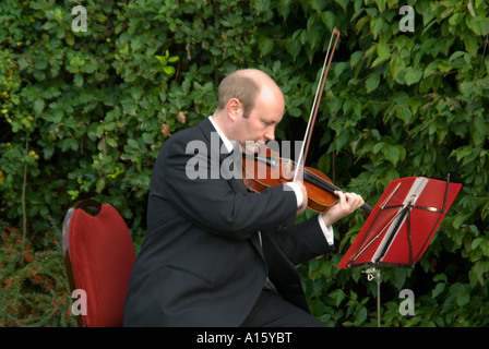 Chiudere orizzontale di un violinista professionista giocando un violino al di fuori in un giardino. Foto Stock