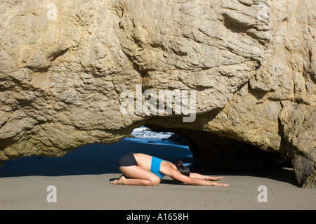 Giovane donna a praticare yoga sulla spiaggia rocciosa Foto Stock
