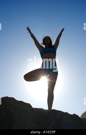 Giovane donna a praticare yoga sulla spiaggia rocciosa Foto Stock