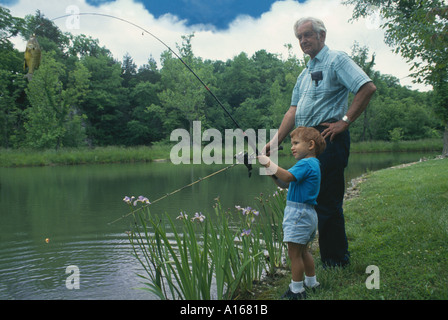 Successo! Nonno e nipote lavorano insieme per catturare un pesce su un giorno iidyllic su un laghetto di estate , Midwest USA Foto Stock