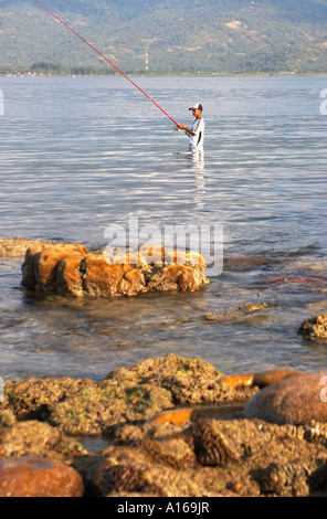 Ragazzo in piedi nella pesca in mare Foto Stock