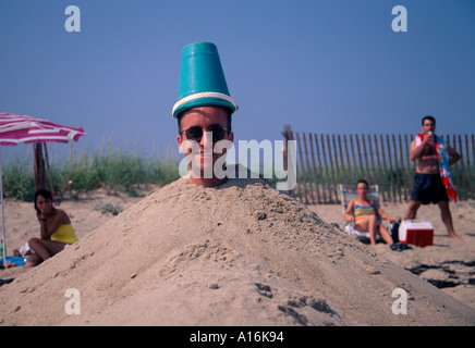 Giovane uomo sepolto nella sabbia Southampton New York Stati Uniti. 35, 40, 45, anni Foto Stock