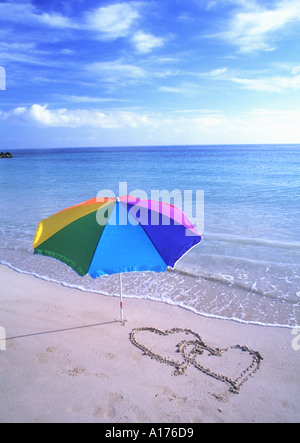 Paradiso tropicale ombrellone sulla spiaggia con cuore disegnato nella sabbia Foto Stock