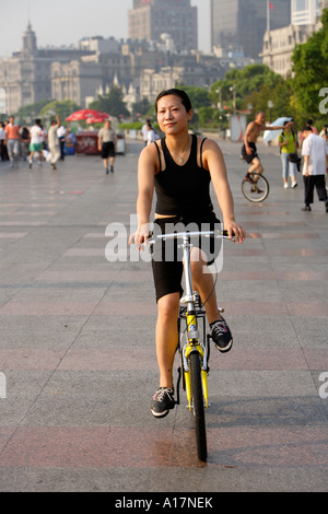 Ragazza sulla bicicletta, la mattina presto, il Bund, Shanghai, Cina. Foto Stock