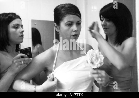 Una sposa guardando nello specchio ottenere pronto per il grande giorno con l aiuto delle sue damigelle Foto Stock