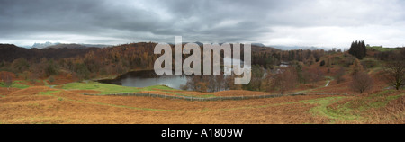 Panoramica orizzontale foto paesaggio di Tarn Hows nel Lake District inglese con alberi e neve in autunno Foto Stock