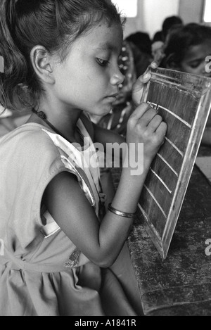 B/N di una giovane ragazza che impara a scrivere su una lavagna in una scuola per bambini di strada. Calcutta, India Foto Stock