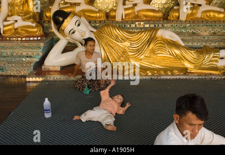 I pellegrini Shwedagon Paya tempio, madre e bambino riposano lontano dal sole. Buddha sdraiato in uno dei templi. Yangon, Myanmar Foto Stock