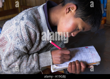 India Bengala Occidentale Himalaya gamma area di Darjeeling Singalila trek scuola nepalese boy iscritto il suo lavoro a casa nel suo exercice prenota whi Foto Stock