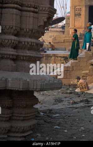 India Uttar Pradesh Gange valley Varanassi drawning tempio di pietra in rgd femmina con i pellegrini in preghiera verso il sole in bkgd Foto Stock