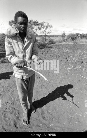 B/W di un diviner d'acqua alla ricerca del posto migliore per scavare un pozzo usando un ramoscello a forchetta. Nr Gweru, Zimbabwe Foto Stock