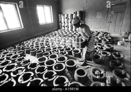 B/W di una donna che mette Upesi creta stufe ad asciugare in deposito prima di forno che spara ad una cooperativa di donne. Kisumu, Kenya Foto Stock