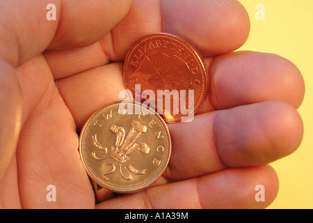 British 2p due penny monete in mano un piccolo cambiamento cambiamento allentato coppers contanti Foto Stock