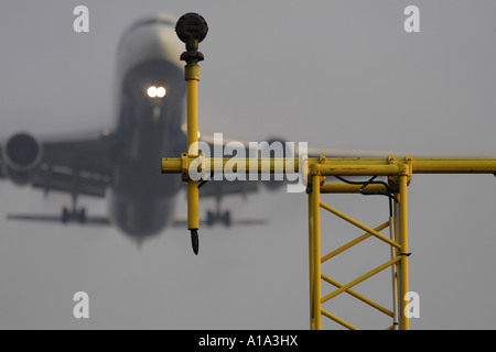 Pista di aeroporto di sbarco delle luci di avvicinamento con passeggeri commerciale piano a getto attorno alla terra in misty meteo Foto Stock