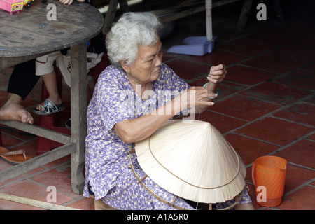 Donna anziana la cucitura di un tradizionale hat, Delta del Mekong, Vietnam Foto Stock