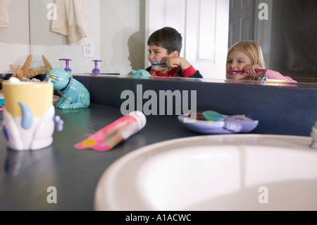 La riflessione a specchio del fratello e sorella di spazzolare i denti Foto Stock