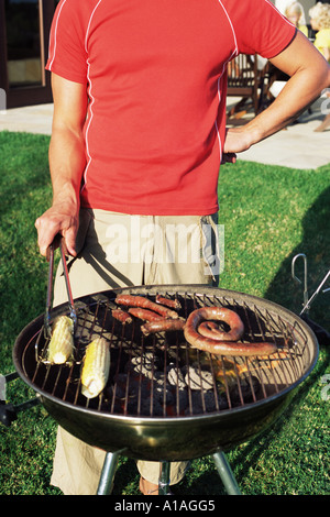 Uomo di cottura degli alimenti su un barbecue Foto Stock