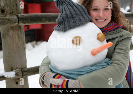 Donna che abbraccia un pupazzo di neve Foto Stock