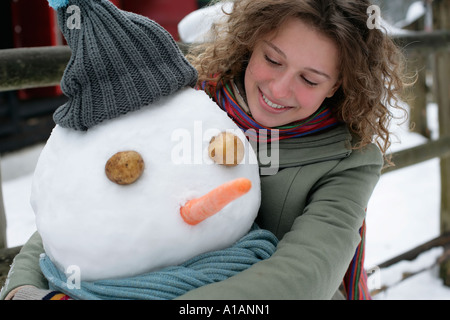 Donna che abbraccia un pupazzo di neve Foto Stock