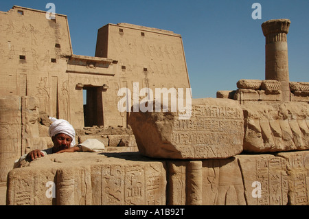 Uomo egiziano in mezzo alle rovine dell'antico tempio di Edfu dedicato al dio falco Horus, costruito nel periodo Tolemaico fra il 237 e il 57 A.C. Egitto Foto Stock