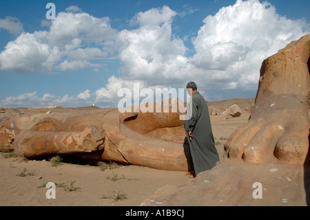 Un uomo egiziano sorge da frammenti scultorei, recuperati dagli scavi presso l'antico tempio di Tanis, nel delta orientale del Nilo Egitto Foto Stock