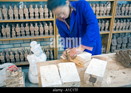 Cina Xi'an femmina lavoratore cinese si apre lo stampo di argilla contenente i modelli in miniatura di guerrieri di terracotta al negozio di souvenir. Foto Stock