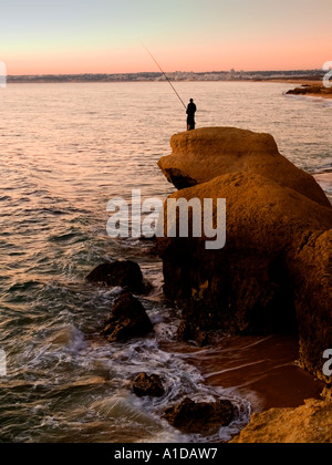 La pesca con lenza in mare nel tramonto a spiaggia di Galé circa 7 km ad ovest di Albufeira Algarve Portogallo Foto Stock