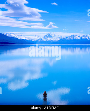 Lone figura in piedi (in acqua) che si affaccia sul Lago Pukaki verso Monte Cook (distanza), Isola del Sud, Nuova Zelanda Foto Stock